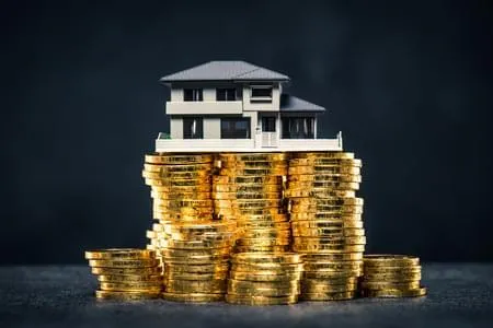 A house sitting on top of stacks of gold coins.