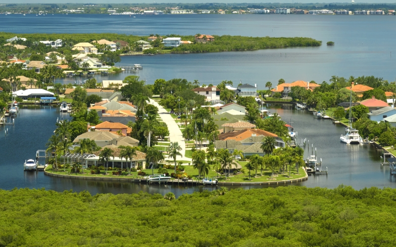 Aerial view of rural private houses in remote suburbs located near Florida wildlife wetlands with green vegetation on sea bay shore. Living close to nature concept.